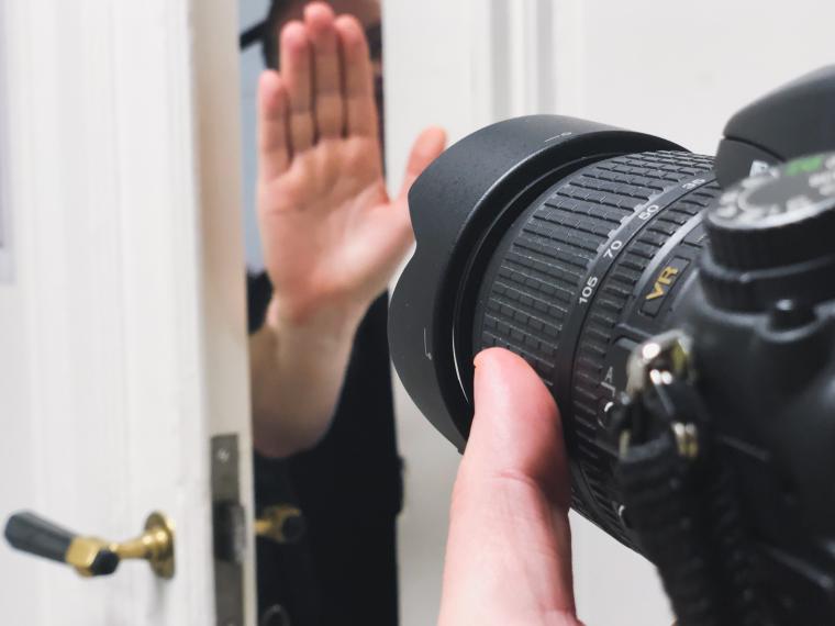 Hand som stoppar fotograf att ta bilder in genom dörröppning