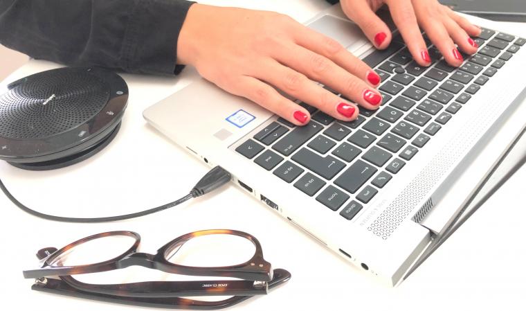 Händer på tangentbord, glasögon bredvid